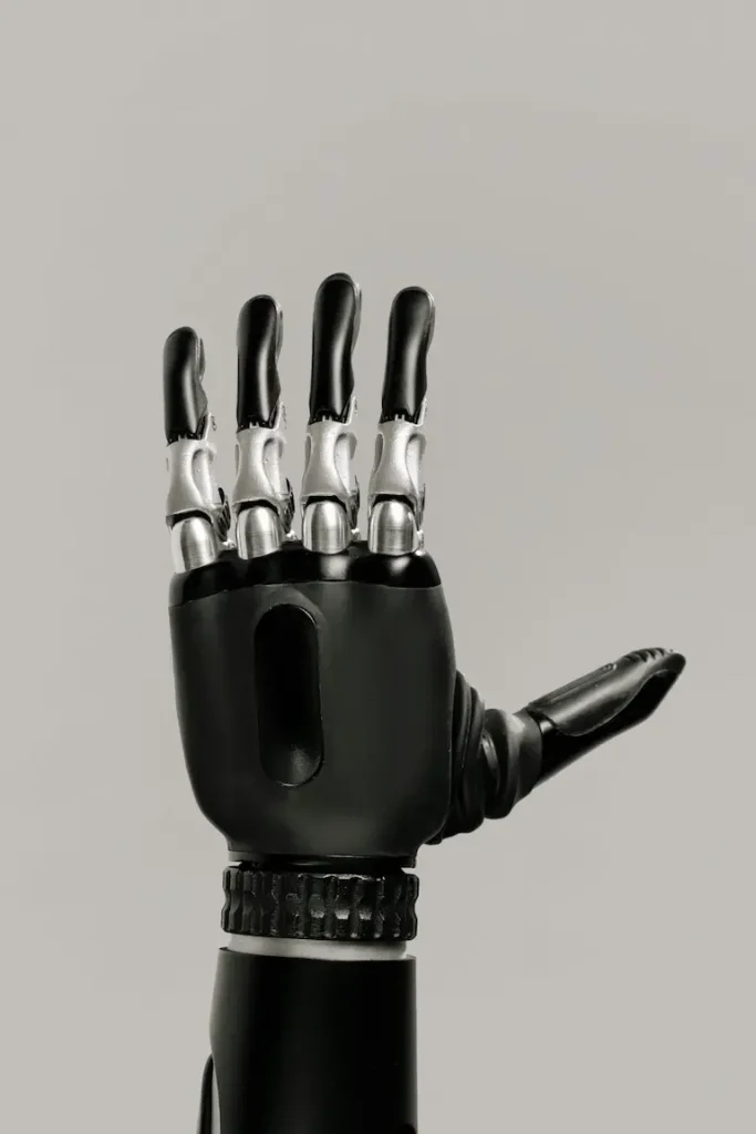 Moderne Handprothese mit ausgestreckten Fingern, fotografiert vor grauem Hintergrund - als Symbol für motorische Unterstützung durch technische Hilfsmittel.